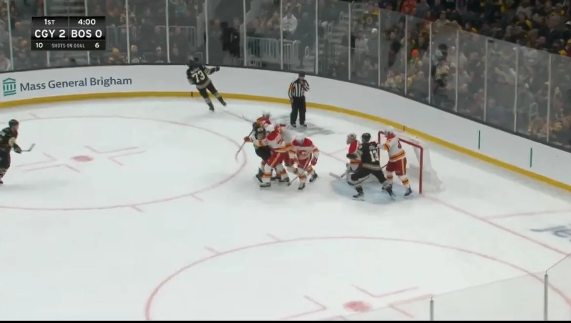 Flames rookie forward punching Bruins captain Brad Marchand in the face during a scrum.