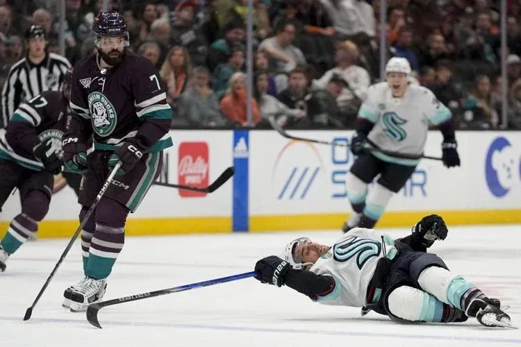 Seattle Kraken forward Brandon Tanev on the ice after a tough hip check from Anaheim Ducks' Radko Gudas in a game.