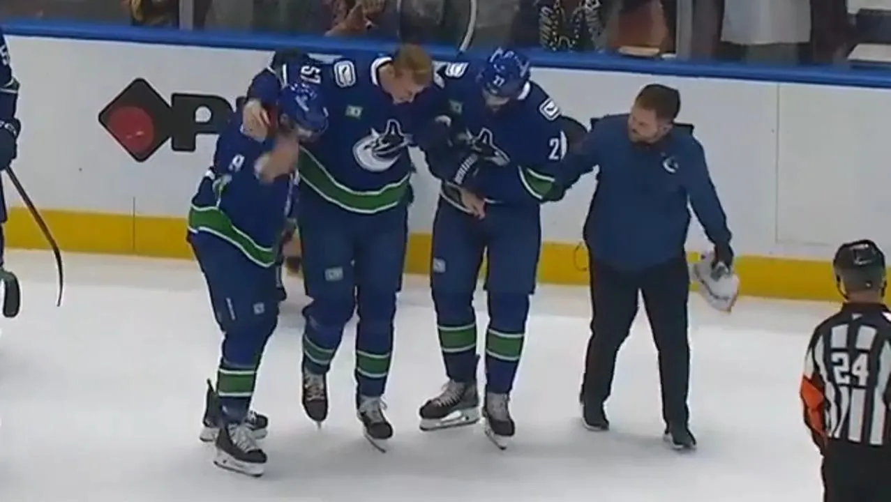Tyler Myers being helped off the ice by his teammates in a game between the Vancouver Canucks and the Philadelphia Flyers.