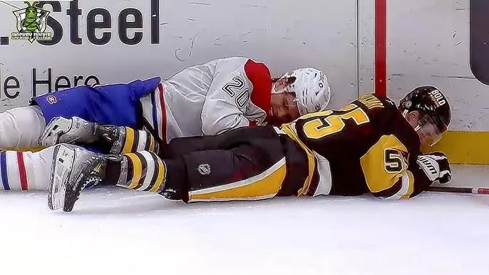 Juraj Slafkovsky of the Montreal Canadiens grimaces in pain after a hard hit from Noel Acciari of the Pittsburgh Penguins