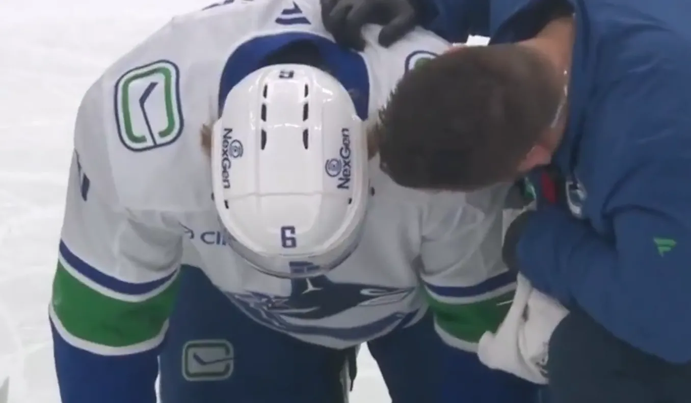 Vancouver Canucks forward Brock Boeser on the ice with the team trainer after taking a high hit from Kings forward Tanner Jeannot