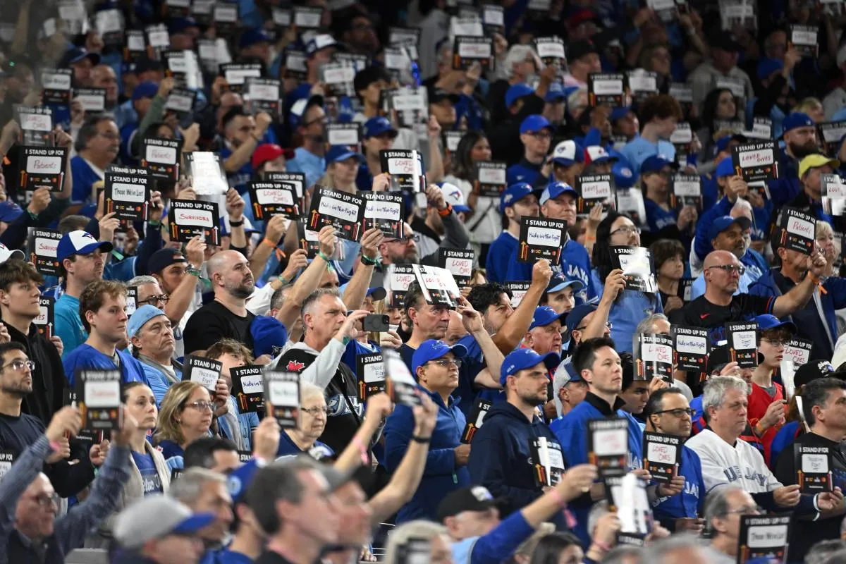 Fans hold up signs as part of recognition for Stand Up to Cancer after the fifth inning during game two of the 2025 MLB World Series between the Los Angeles Dodgers and the Toronto Blue Jays at Rogers Centre.