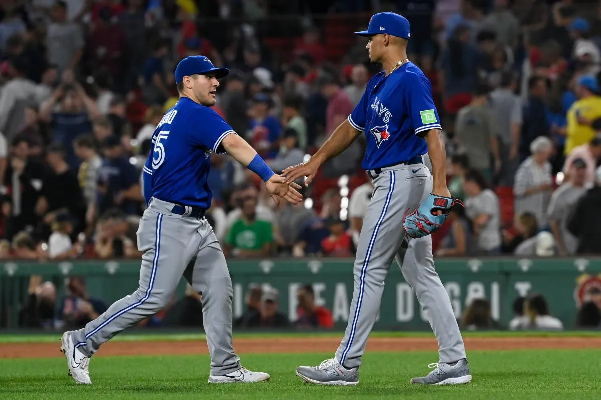Toronto Blue Jays relief pitcher Jordan Hicks (12) celebrates a win with second baseman Santiago Espinal (5) during the ninth inning at Fenway Park.