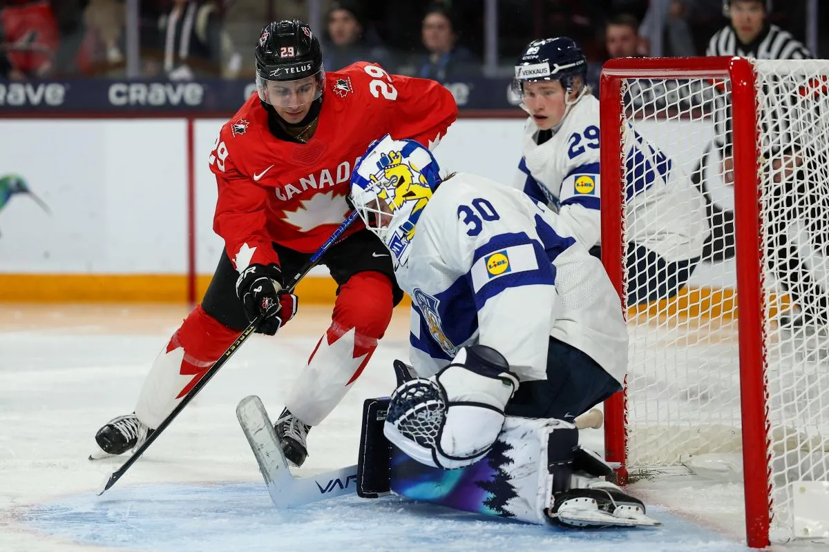 Le gardien finlandais Petteri Rimpinen (30) effectue un arr&ecirc;t sur un tir de l'attaquant canadien Michael Hage (29) lors de la deuxi&egrave;me p&eacute;riode du match de groupe du Championnat mondial junior 2026 de l'IIHF au 3M Arena.