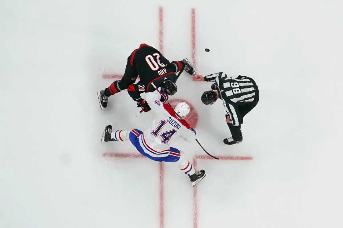 Sebastian Aho (20), centre des Hurricanes de la Caroline, et Nick Suzuki (14), centre des Canadiens de Montr&eacute;al, s'affrontent lors d'une mise au jeu au cours de la premi&egrave;re p&eacute;riode au Lenovo Center.