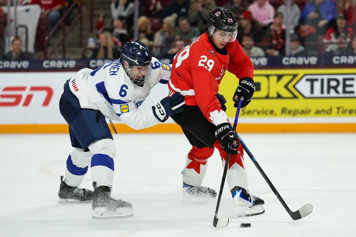 L'attaquant canadien Michael Hage (29) patine avec la rondelle tandis que le d&eacute;fenseur finlandais Juho Piiparinen (6) d&eacute;fend pendant la deuxi&egrave;me p&eacute;riode du match de groupe du Championnat mondial junior 2026 de l'IIHF au 3M Arena.