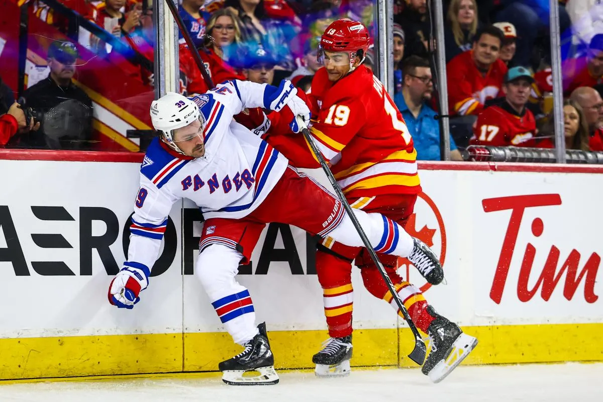 Le centre des Rangers de New York, Sam Carrick (39), et le d&eacute;fenseur des Flames de Calgary, Zayne Parekh (19), se disputent la rondelle durant la troisi&egrave;me p&eacute;riode au Scotiabank Saddledome.