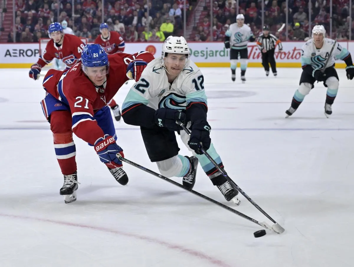 Le 14 octobre 2025, &agrave; Montr&eacute;al, au Qu&eacute;bec, le joueur de l'&eacute;quipe des Seattle Kraken, Tye Kartye (12), joue la rondelle et le d&eacute;fenseur des Montr&eacute;al Canadiens, Kaiden Guhle (21), le d&eacute;fend, lors du troisi&egrave;me tiers-temps, au Bell Centre.