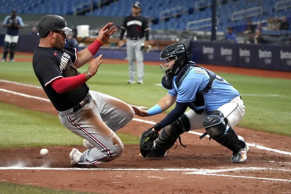 Minnesota Twins infielder Aaron Sabato (96) slides into home safely as Tampa Bay Rays catcher Rene Pinto (50) tries to make the tag during the ninth inning at Tropicana Field.