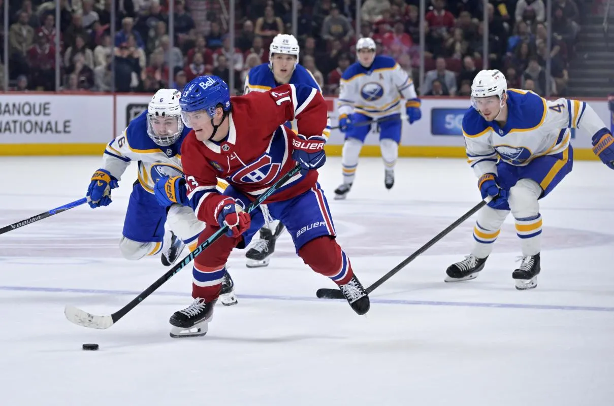 l'attaquant des Canadiens de Montr&eacute;al, Cole Caufield (13), joue la rondelle et le d&eacute;fenseur des Sabres de Buffalo, Zach Benson (6), le d&eacute;fend avec son co&eacute;quipier Bowen Byram (4), lors du troisi&egrave;me tiers-temps au Centre Bell.