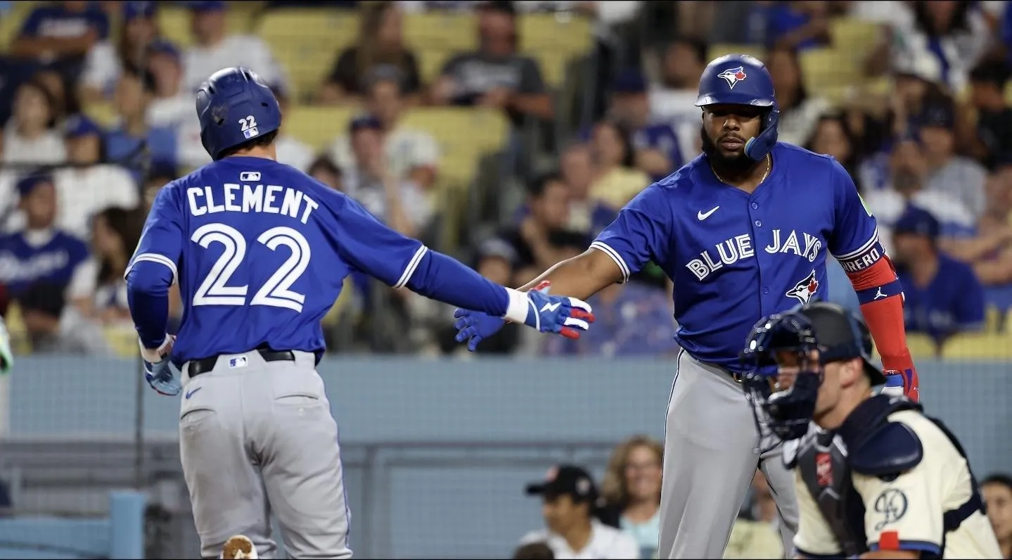 Toronto Blue Jays third baseman Ernie Clement (22) is greeted by designated hitter Vladimir Guerrero Jr. (27, right) after hitting a home run during the eighth inning against the Los Angeles Dodgers at Dodger Stadium.