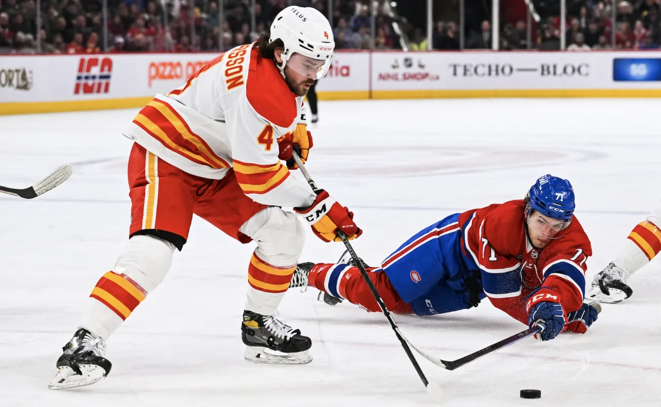Le centre des Canadiens de Montr&eacute;al Jake Evans (71) tente de d&eacute;fendre le palet contre le d&eacute;fenseur des Flames de Calgary Rasmus Andersson (4) pendant la deuxi&egrave;me p&eacute;riode au Centre Bell.