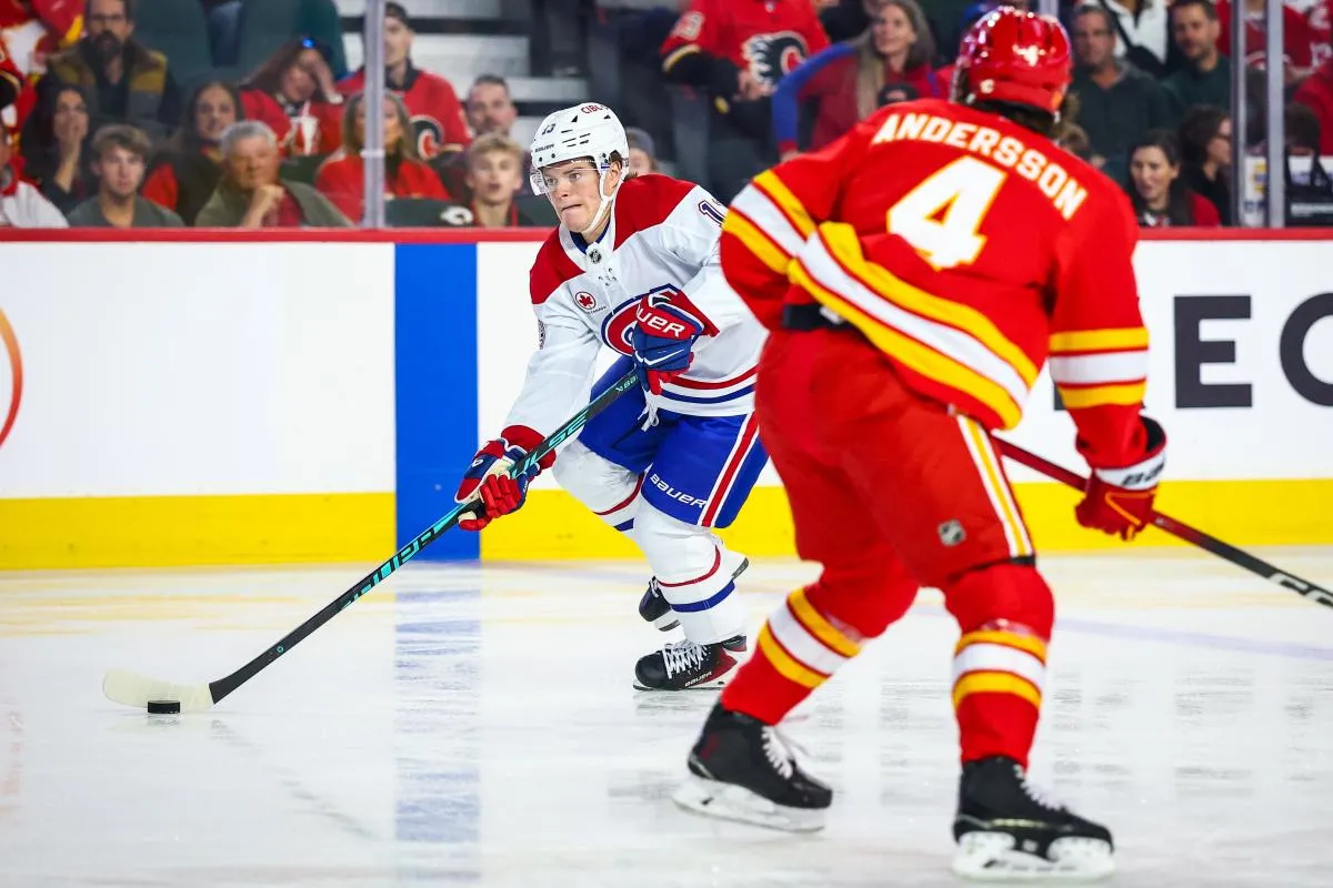 l'attaquant droit des Canadiens de Montr&eacute;al, Cole Caufield (13), contr&ocirc;le la rondelle face au d&eacute;fenseur des Flames de Calgary, Rasmus Andersson (4), lors du premier tiers &agrave; Scotiabank Saddledome.