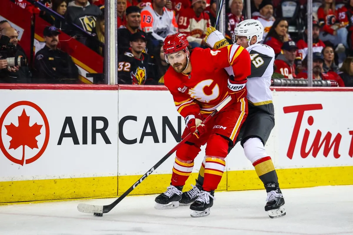 Calgary Flames defenseman Rasmus Andersson (4) and Vegas Golden Knights left wing Ivan Barbashev (49) battle for the puck during the first period at Scotiabank Saddledome.