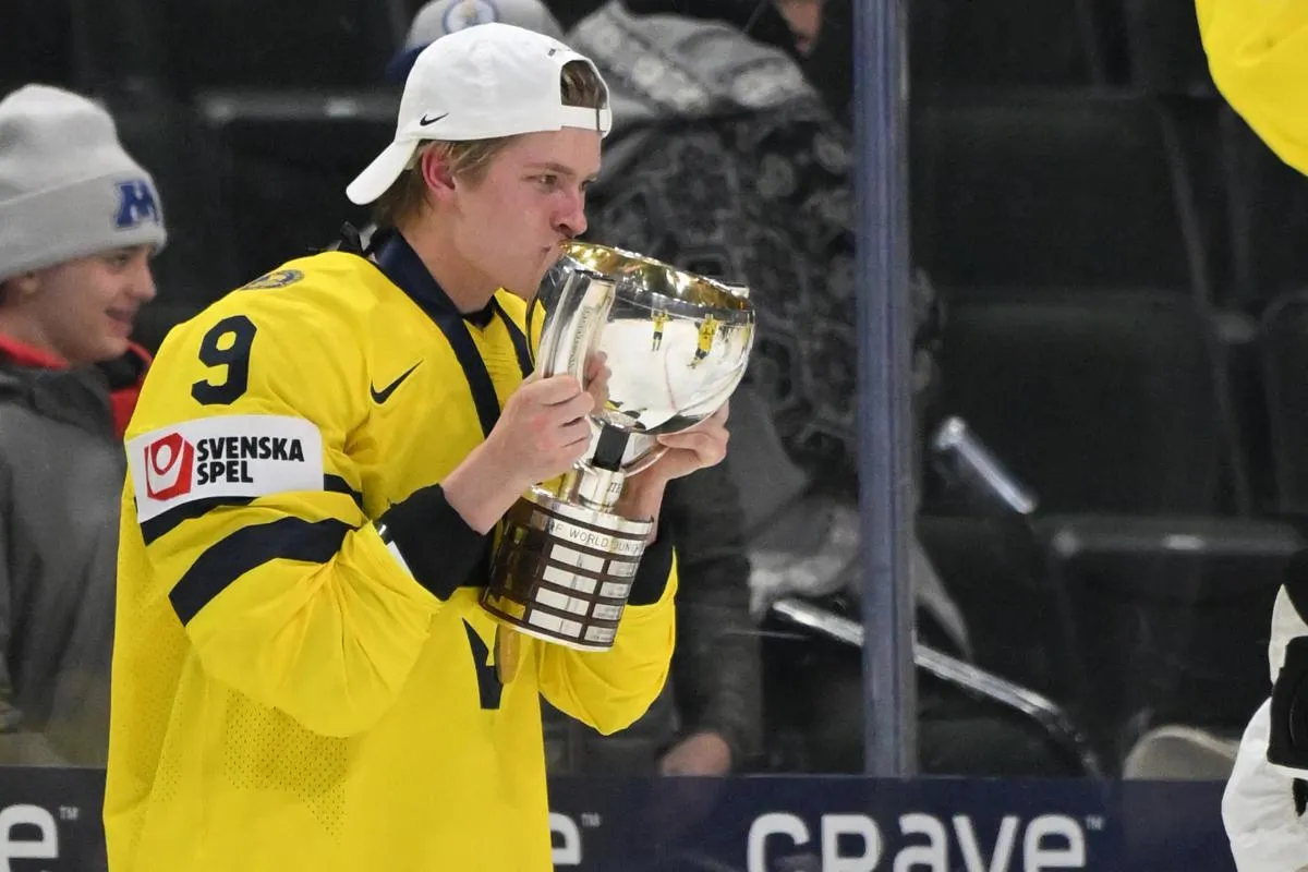 Sweden defensemen Victor Johansson (9) kisses the first place trophy after defeating Czechia in the final of the 2026 IIHF World Junior Championship ice hockey tournament at Grand Casino Arena