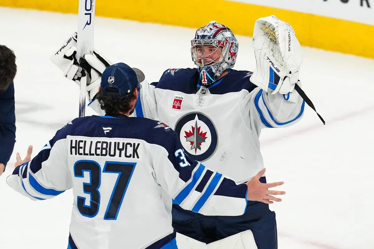 Winnipeg Jets goaltender Eric Comrie (1) celebrates with Winnipeg Jets goaltender Connor Hellebuyck (37) after shutting out the Vegas Golden Knights 4-0 at T-Mobile Arena.