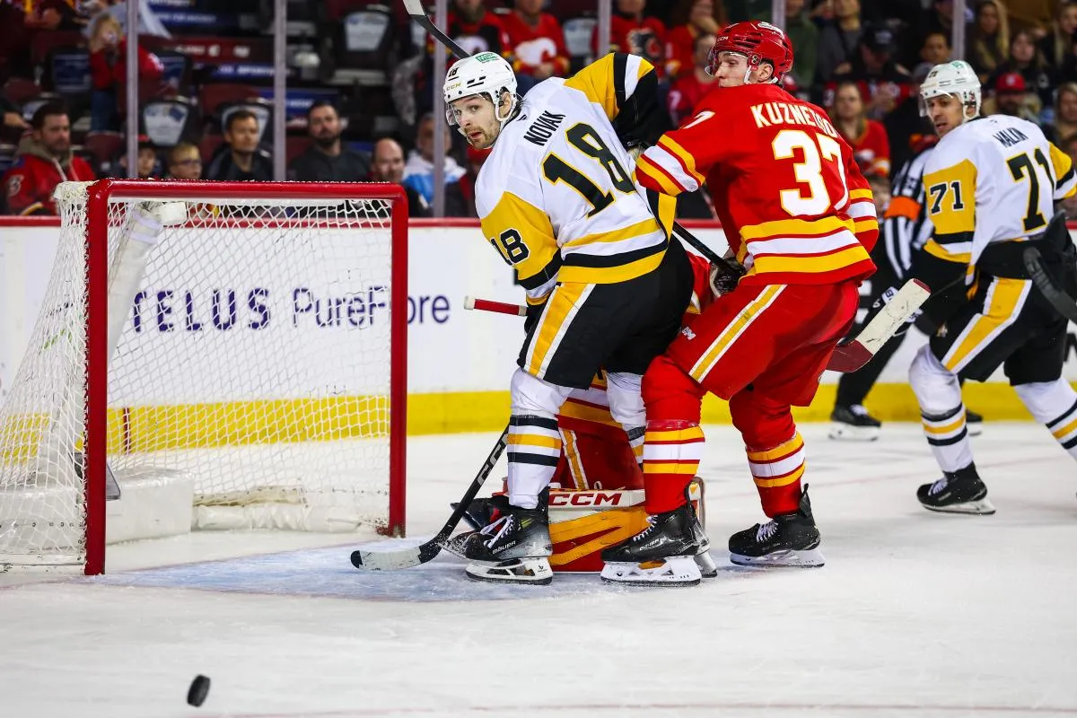 Pittsburgh Penguins center Tommy Novak (18) and Calgary Flames defenseman Yan Kuznetsov (37) fight for position in front of Calgary Flames goaltender Dustin Wolf (32) during the third period at Scotiabank Saddledome.