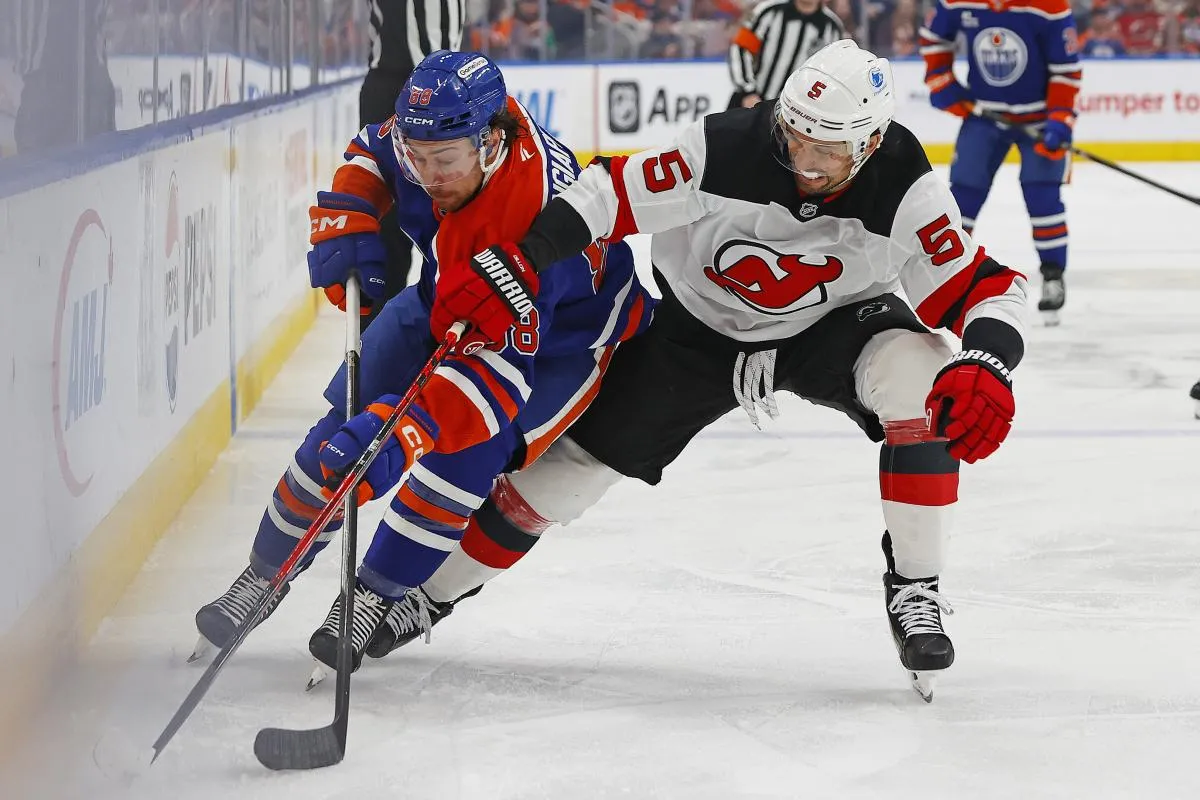 Edmonton Oilers forward Andrew Mangiapane (88) and New Jersey Devils defensemen Brendan Dillon (5) battle along the boards for a loose puck during the first period at Rogers Place.