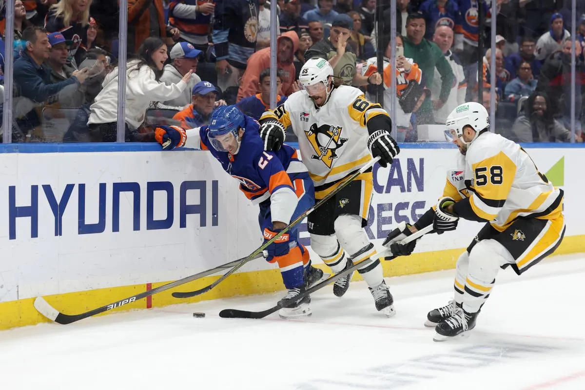 New York Islanders center Kyle Palmieri (21) fights for the puck against Pittsburgh Penguins defensemen Erik Karlsson (65) and Kris Letang (58) during overtime at UBS Arena.