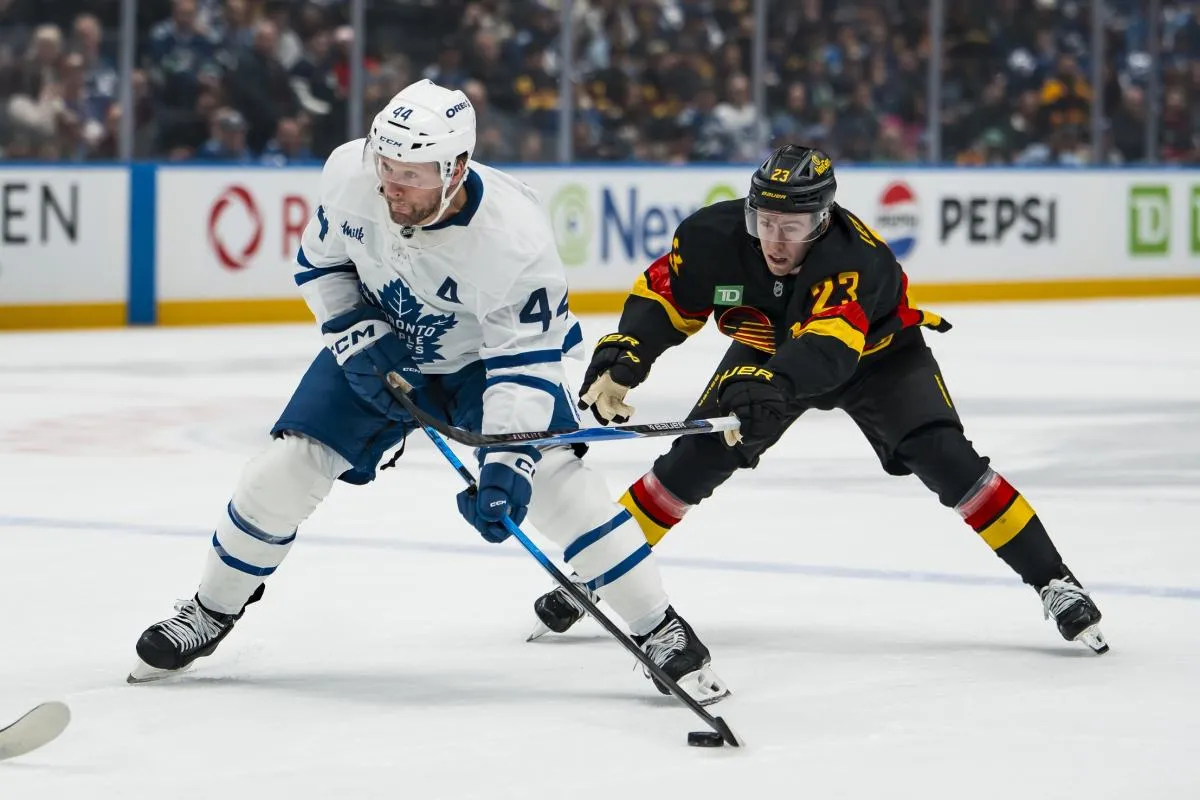 Vancouver Canucks forward Jonathan Lekkerimaki (23) stick checks Toronto Maple Leafs defenseman Morgan Rielly (44) in the first period at Rogers Arena