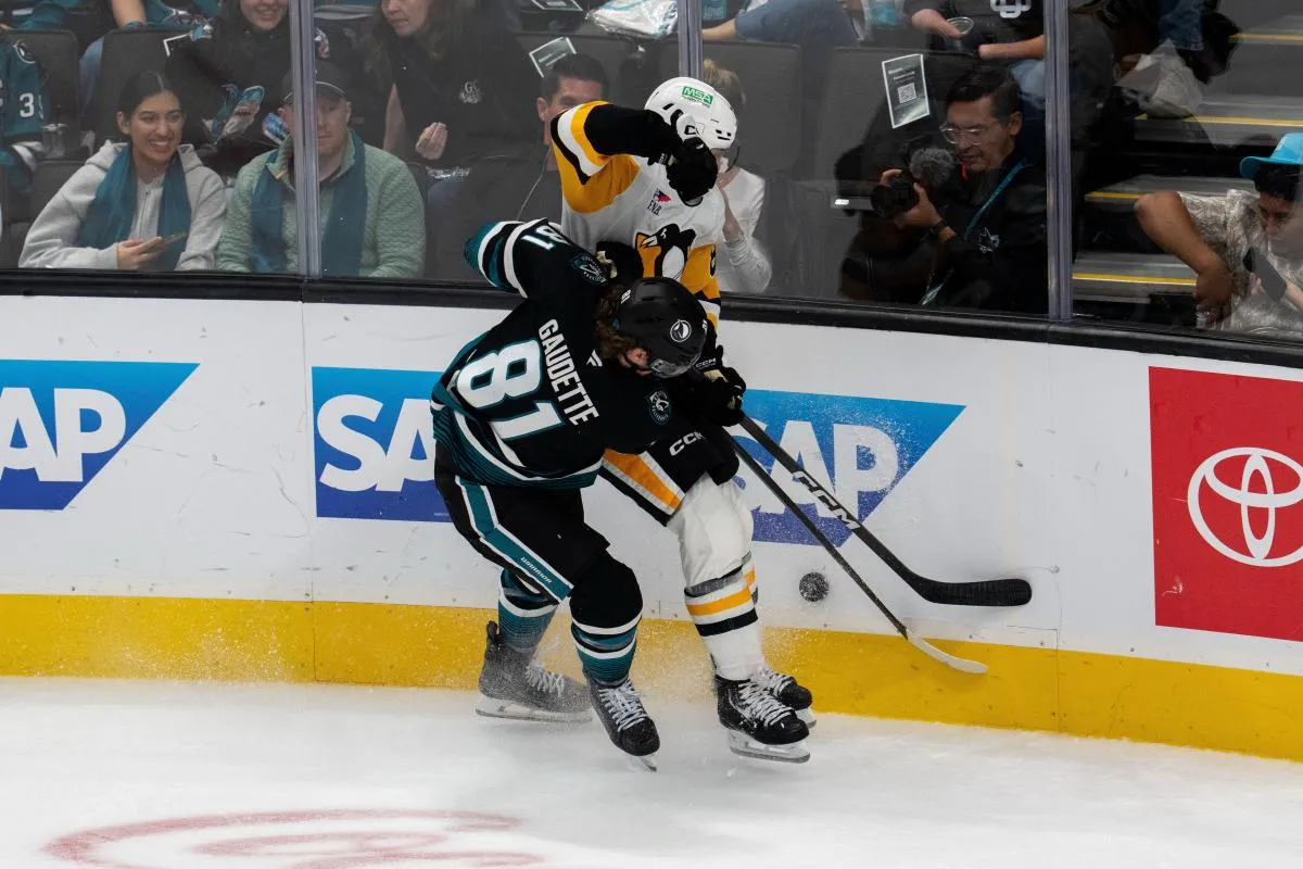 Pittsburgh Penguins defenseman Caleb Jones (82) is checked into the boards while battling for the puck by San Jose Sharks right wing Adam Gaudette (81) during the third period at SAP Center at San Jose.