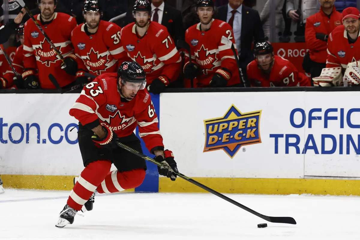 [teammates look on, Team Canada forward Brad Marchand (63) carries the puck during the 4 Nations Face-Off ice hockey championship game against the United States at TD Garden.