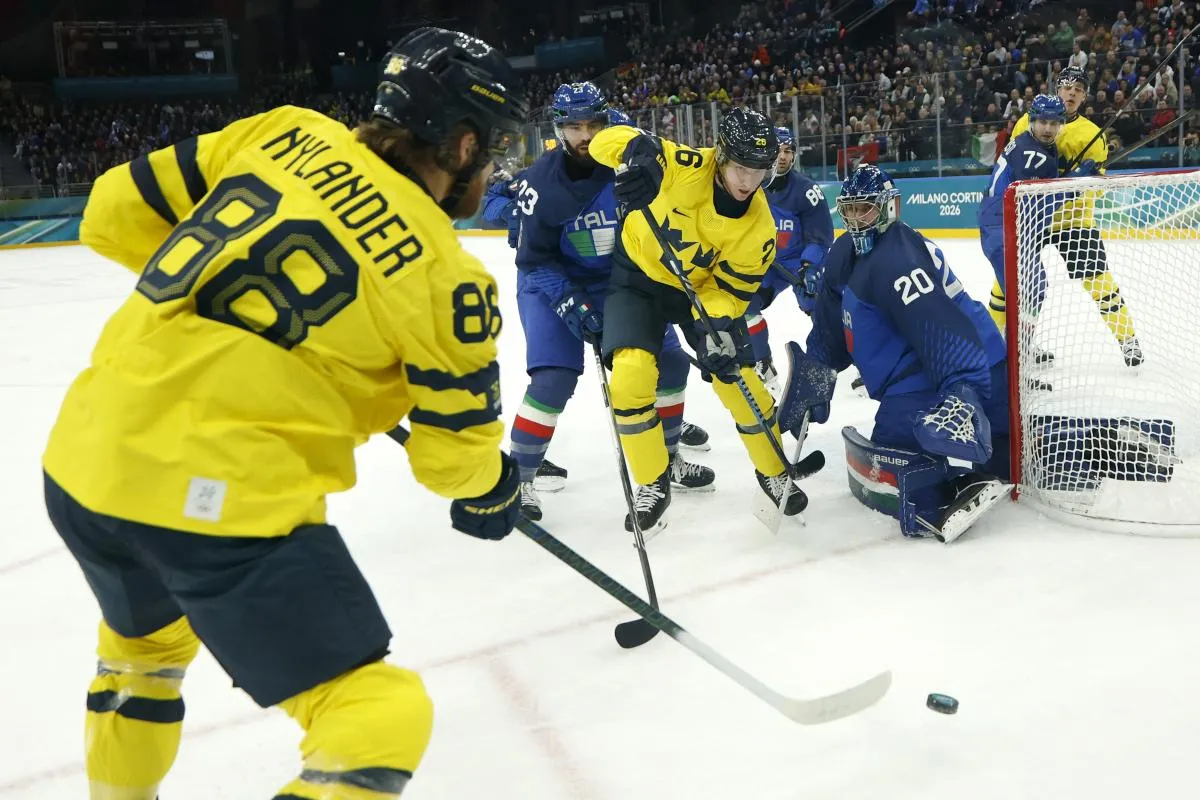 William Nylander of Sweden and Rasmus Dahlin of Sweden in action with Damian Clara of Italy and Giovanni Morini of Italy in men's ice hockey group B play during the Milano Cortina 2026 Olympic Winter Games at Milano Santagiulia Ice Hockey Arena