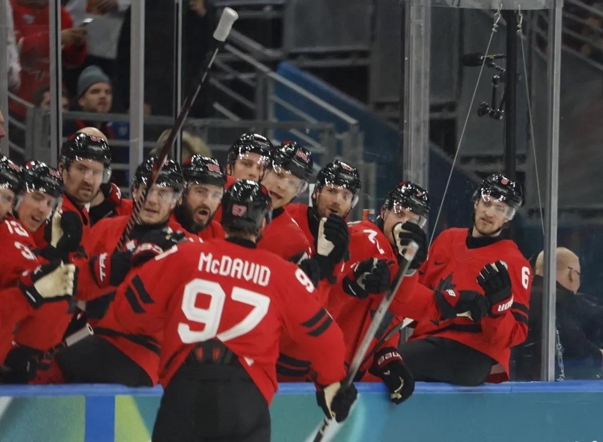 Connor McDavid of Canada celebrates with teammates after scoring their first goal against Switzerland in men's ice hockey group A play during the Milano Cortina 2026 Olympic Winter Games at Milano Santagiulia Ice Hockey Arena.