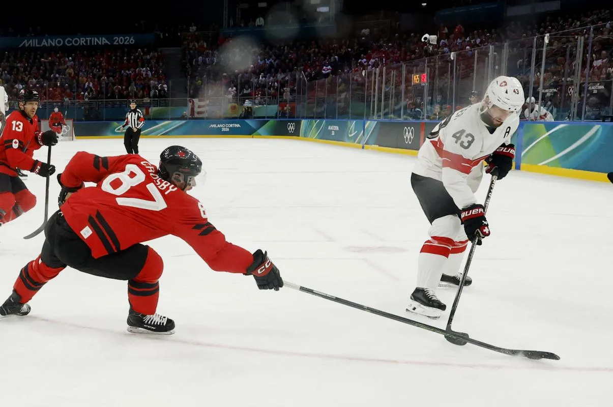 Andrea Glauser of Switzerland in action with Sidney Crosby of Canada in men's ice hockey group A play during the Milano Cortina 2026 Olympic Winter Games at Milano Santagiulia Ice Hockey Arena.