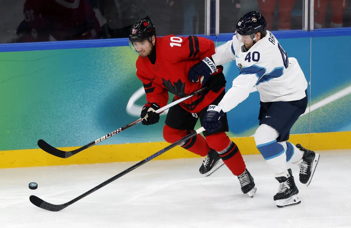 Nick Suzuki of Canada in action with Joel Armia of Finland in a men's ice hockey semifinal during the Milano Cortina 2026 Olympic Winter Games at Milano Santagiulia Ice Hockey Arena.