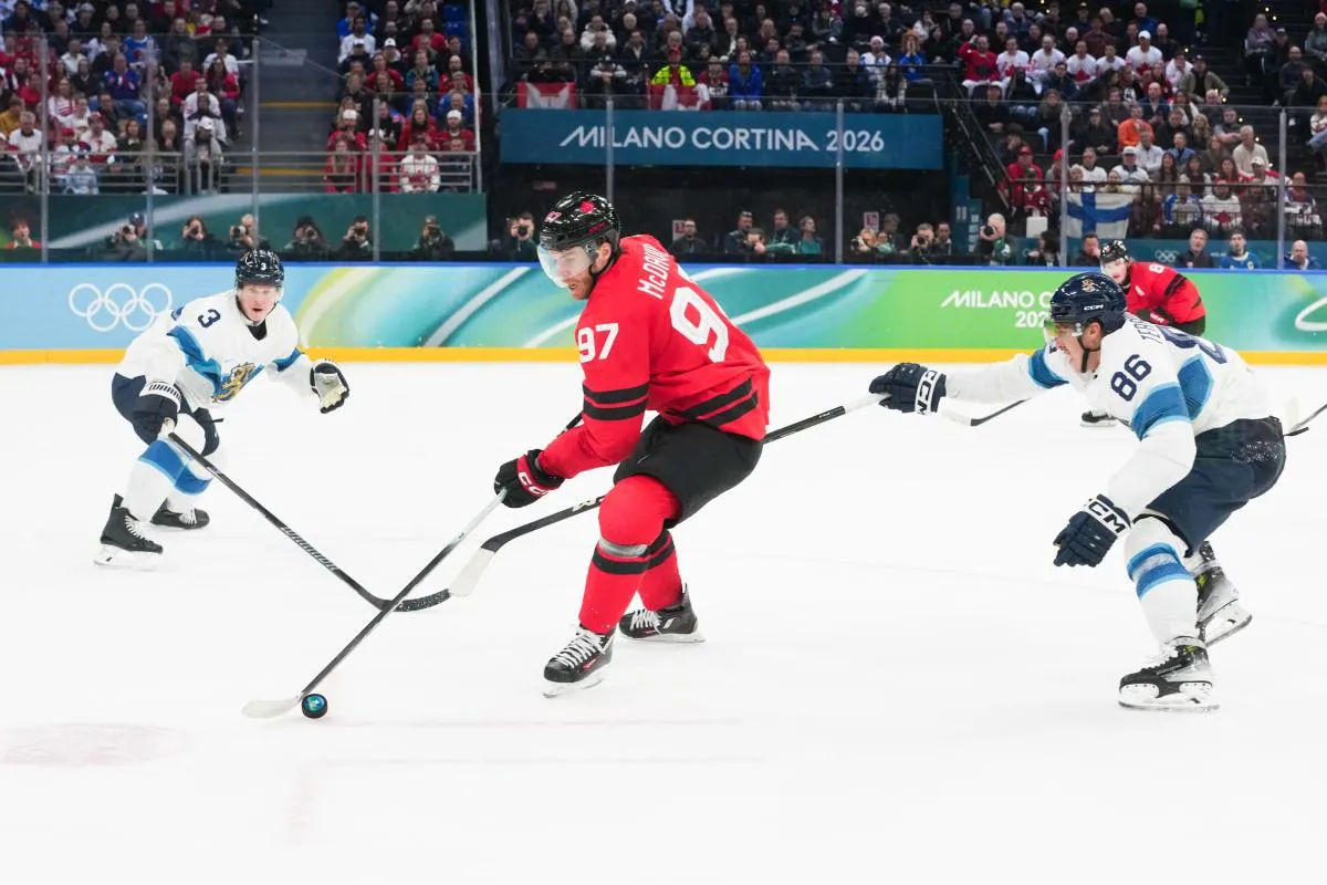 Connor McDavid (97) of Canada moves the puck up the ice as Teuvo Teravainen (86) of Finland defends during the second period in a men's ice hockey semifinal during the Milano Cortina 2026 Olympic Winter Games at Milano Santagiulia Ice Hockey Arena.