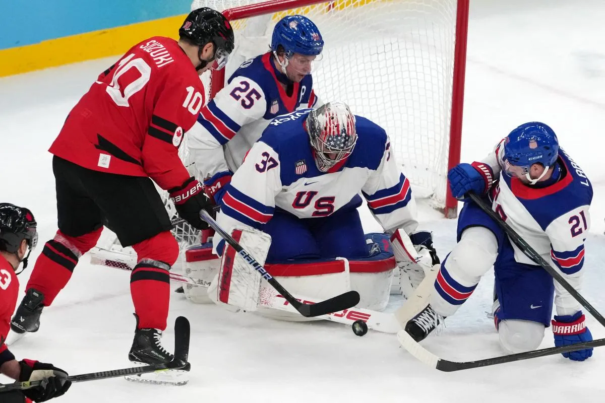 Connor Hellebuyck et Dylan Larkin, des &Eacute;tats-Unis, tentent de s'emparer du palet face &agrave; Nick Suzuki, du Canada, lors du match pour la m&eacute;daille d'or masculine de hockey sur glace des Jeux olympiques d'hiver de Milan-Cortina 2026, &agrave; la patinoire Milano Santagiulia Ice Hockey Arena.