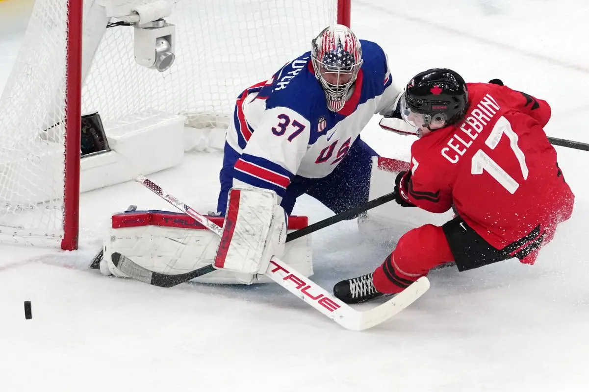 Connor Hellebuyck of the United States battles for the puck against Macklin Celebrini of Canada during the men's ice hockey gold medal game during the Milano Cortina 2026 Olympic Winter Games at Milano Santagiulia Ice Hockey Arena.