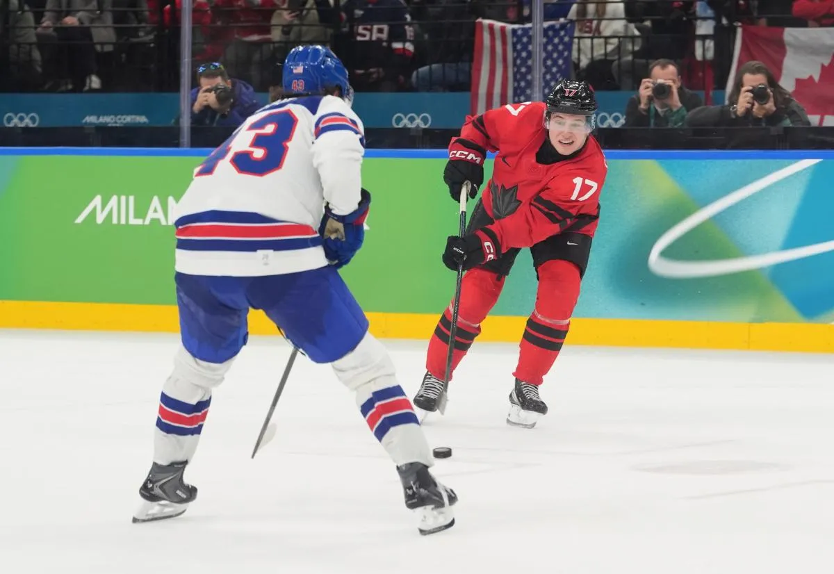 Macklin Celebrini (17) of Canada in action against Quinn Hughes (43) of the United States in the men's ice hockey gold medal game during the Milano Cortina 2026 Olympic Winter Games at Milano Santagiulia Ice Hockey Arena.