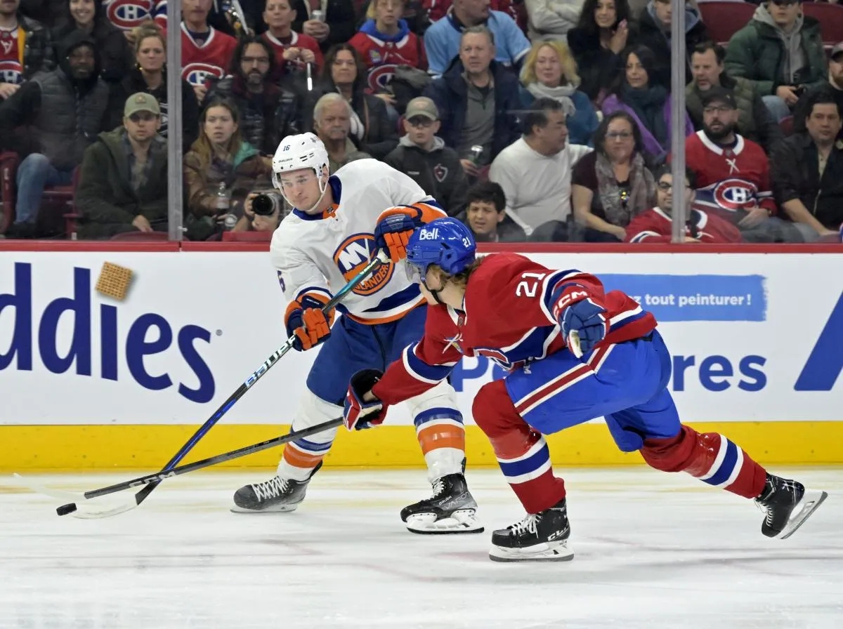 L'attaquant des Islanders de New York Julien Gauthier (16) joue la rondelle et le d&eacute;fenseur des Canadiens de Montr&eacute;al Kaiden Guhle (21) d&eacute;fend pendant la premi&egrave;re p&eacute;riode au Centre Bell.