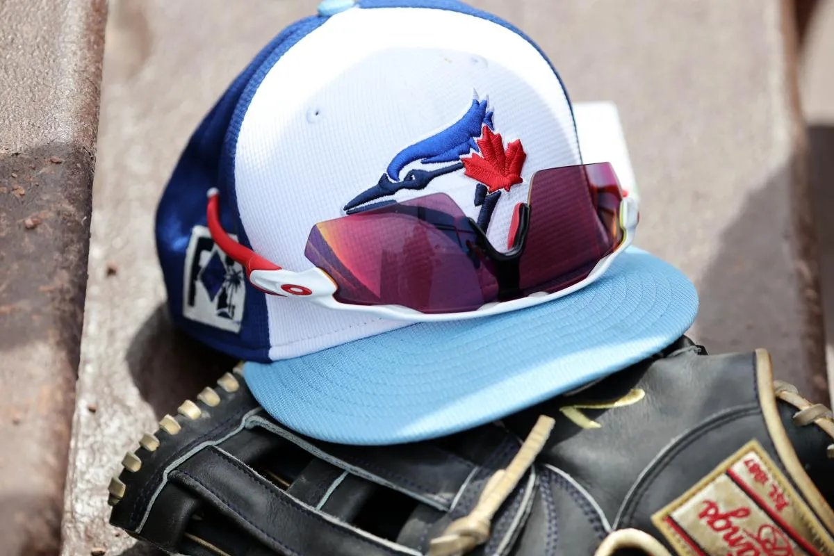 A detail view of a Toronto Blue Jays hat , sunglasses and glove laying in the dugout against the Atlanta Braves at CoolToday Park.