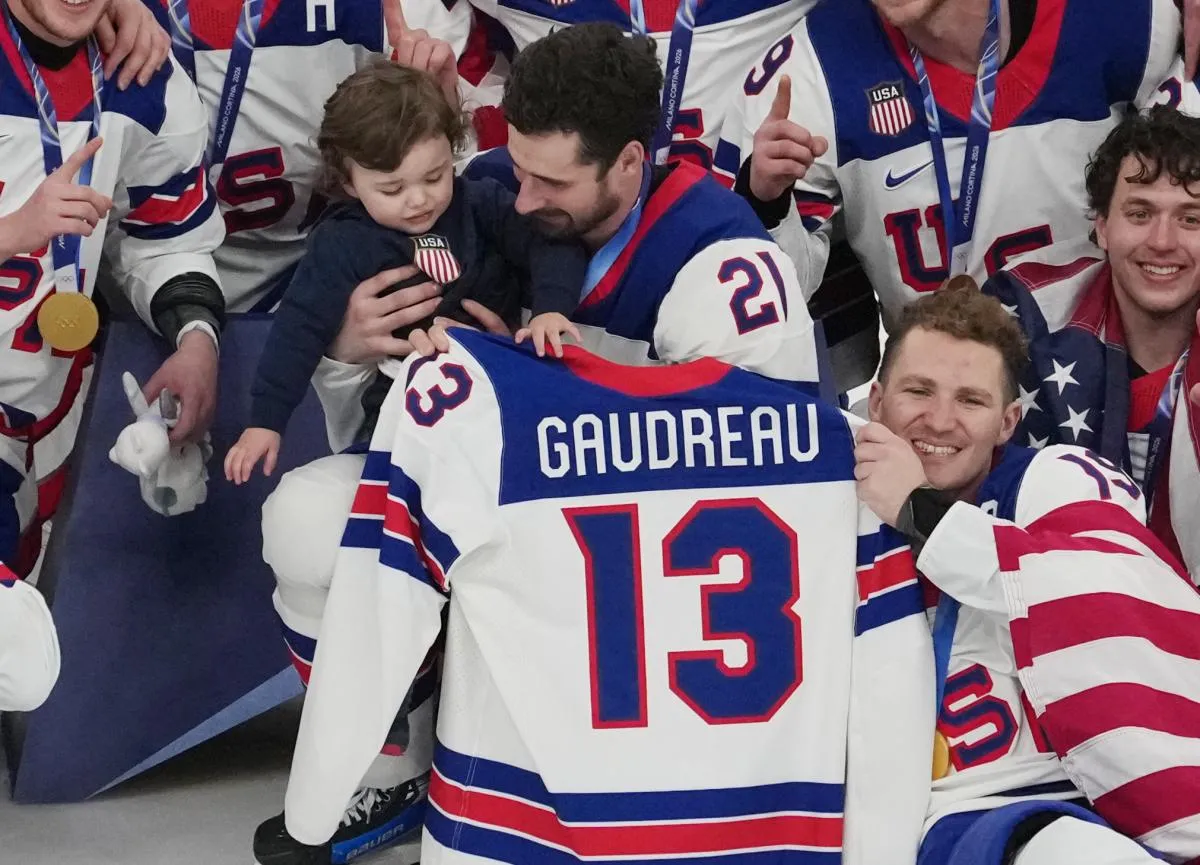 Dylan Larkin (21) holds Johnny Gaudreau Jr, the son of the late Johnny Gaudreau after winning the men's ice hockey gold medal game during the Milano Cortina 2026 Olympic Winter Games at Milano Santagiulia Ice Hockey Arena.