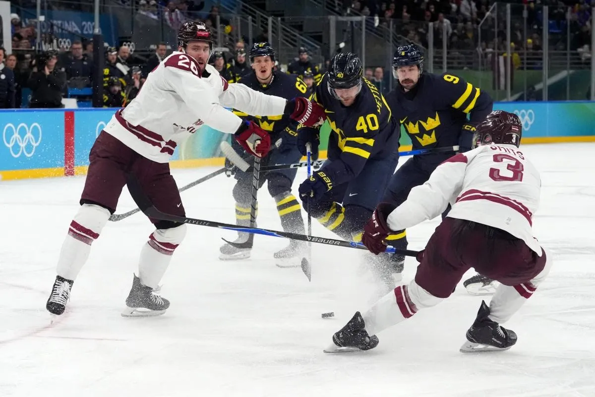 Elias Pettersson of Sweden in action with Uvis Janis Balinskis of Latvia and Alberts Smits of Latvia during a men's ice hockey qualification playoff game during the Milano Cortina 2026 Olympic Winter Games at Milano Santagiulia Ice Hockey Arena