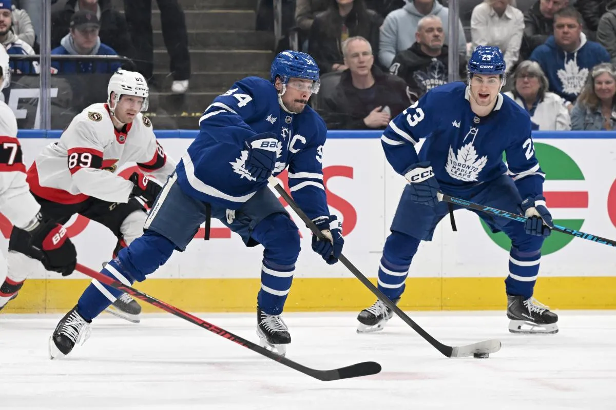 Toronto Maple Leafs forward Auston Matthews (34) passes the puck away from Ottawa Senators forward Lars Eller (89) as forward Matthew Knies (23) looks on in the first period at Scotiabank Arena.