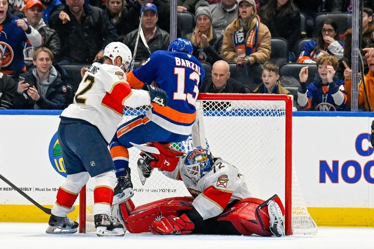 New York Islanders center Mathew Barzal (13) hangs on to the top of the net as Florida Panthers goaltender Sergei Bobrovsky (72) makes a save during the first periodat UBS Arena.