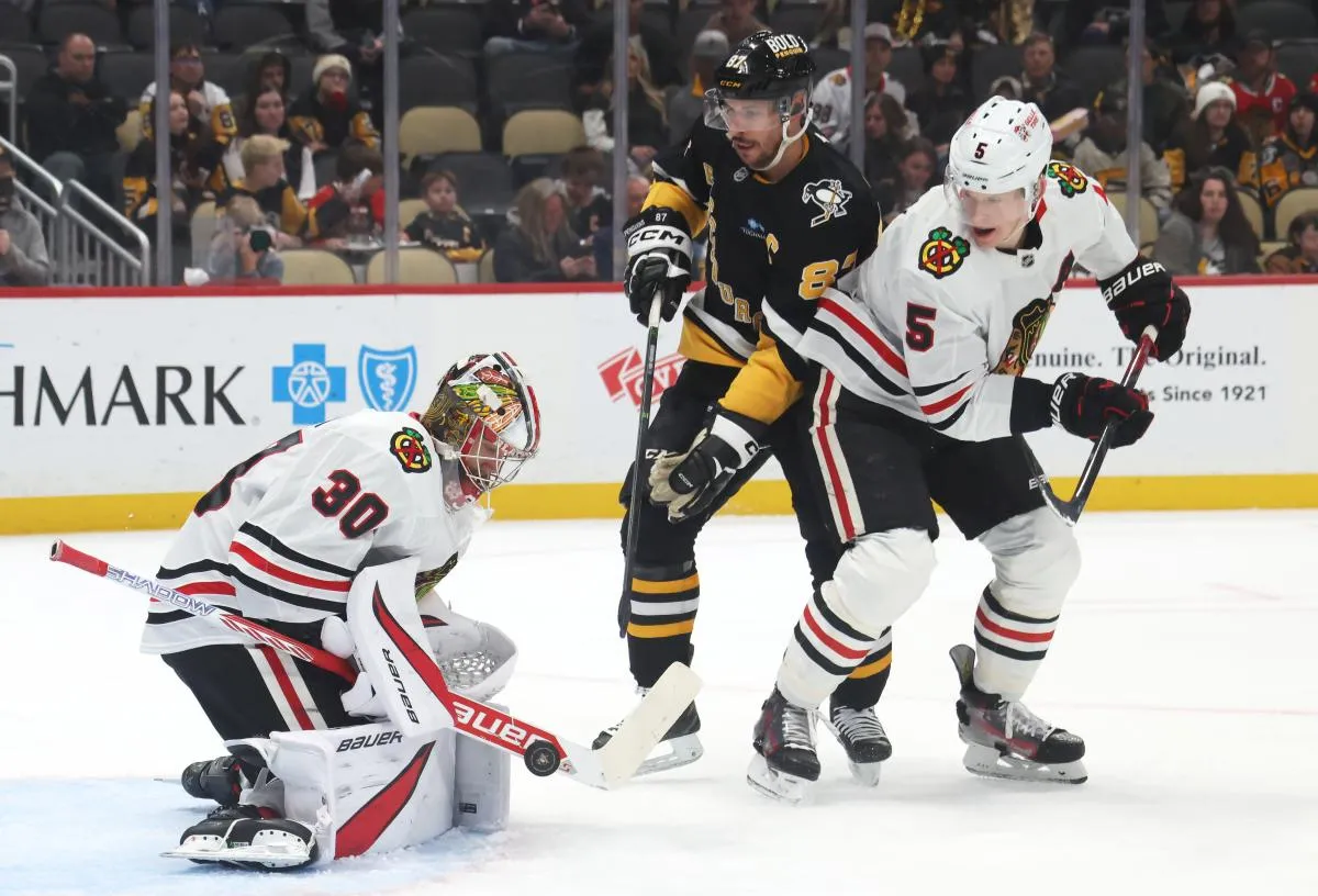 Chicago Blackhawks goaltender Spencer Knight (30) makes a save as defenseman Connor Murphy (5) defends Pittsburgh Penguins center Sidney Crosby (87) during the first period at PPG Paints Arena.