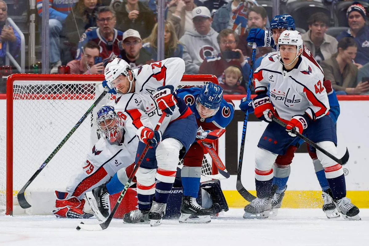 Washington Capitals center Nic Dowd (26) looks to clear the puck ahead of Colorado Avalanche left wing Artturi Lehkonen (62) as goaltender Charlie Lindgren (79) and defenseman Martin Feh&eacute;rv&aacute;ry (42) and center Brock Nelson (11) look on in the third period at Ball Arena.