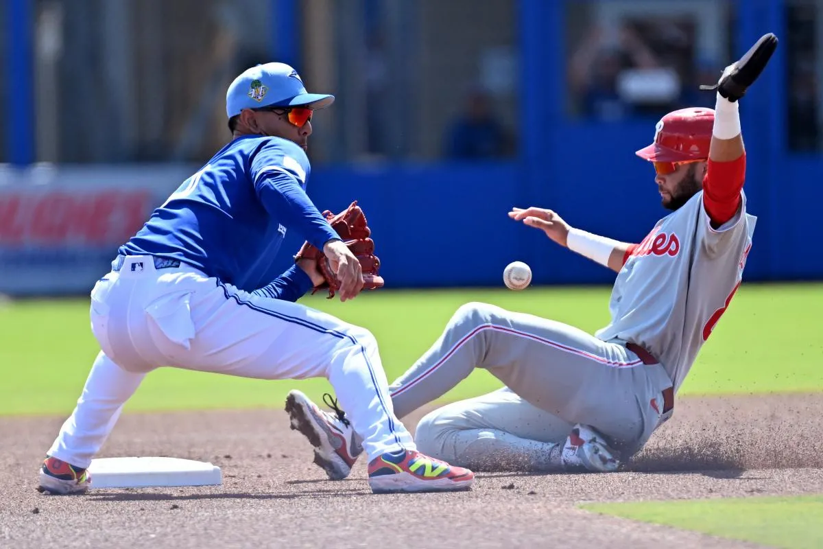 Philadelphia Phillies center fielder Justin Crawford (80) slides into second base as Toronto Blue Jays shortstop Andres Gimenez (0) waits for the ball during spring training at TD Ballpark.