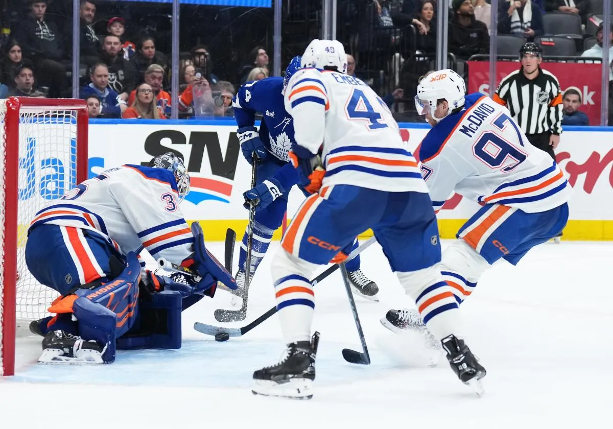 Edmonton Oilers center Connor McDavid (97) battles for the puck with Toronto Maple Leafs center Bobby McMann (74) in front of the net during the third period at Scotiabank Arena.