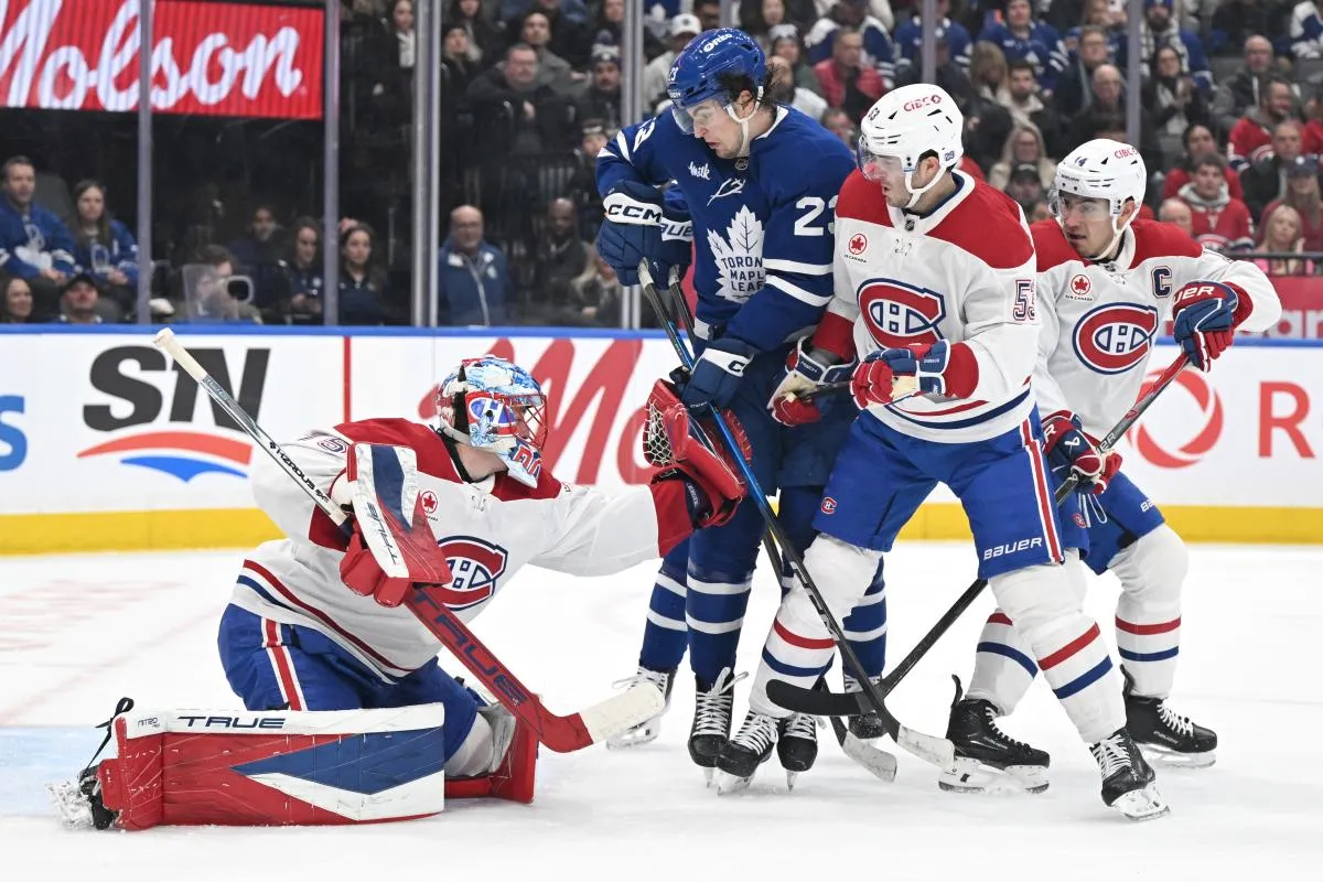 Le gardien des Canadiens de Montr&eacute;al Jakub Dobes (75) effectue un arr&ecirc;t avec son gant tandis que le d&eacute;fenseur Noah Dobson (53) couvre l'attaquant des Maple Leafs de Toronto Matthew Knies (23) lors de la premi&egrave;re p&eacute;riode au Scotiabank Arena.