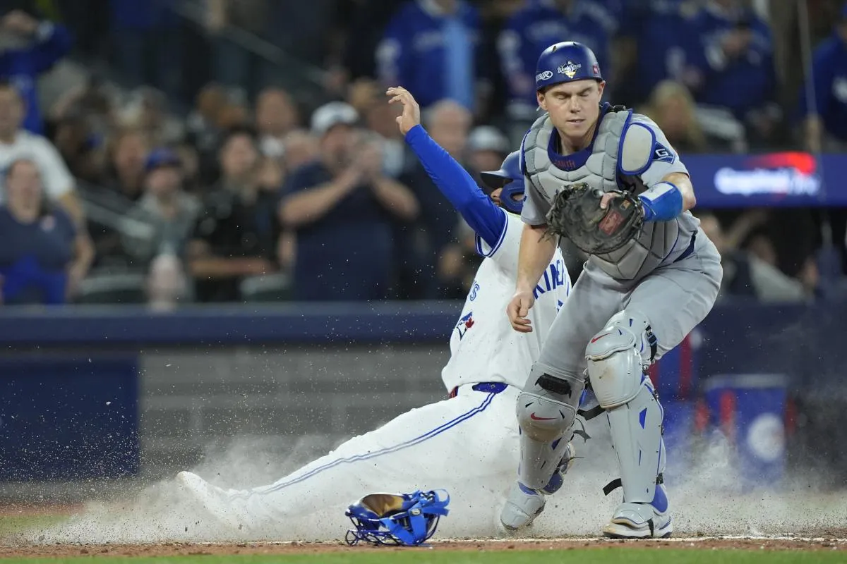 Toronto Blue Jays second baseman Isiah Kiner-Falefa (7) is out against Los Angeles Dodgers catcher Will Smith (16) in the ninth inning during game seven of the 2025 MLB World Series at Rogers Centre.