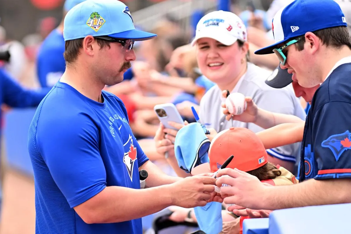 Toronto Blue Jays outfielder Davis Schneider (36) signs autographs before the start of the game against the Florida Marlins during spring training at TD Ballpark.