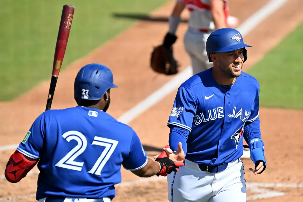 Toronto Blue Jays designated hitter George Springer (4) celebrates with first baseman Vladimir Guerrero Jr. (27) after scoring a run in the third inning against the Philadelphia Phillies during spring training at TD Ballpark.