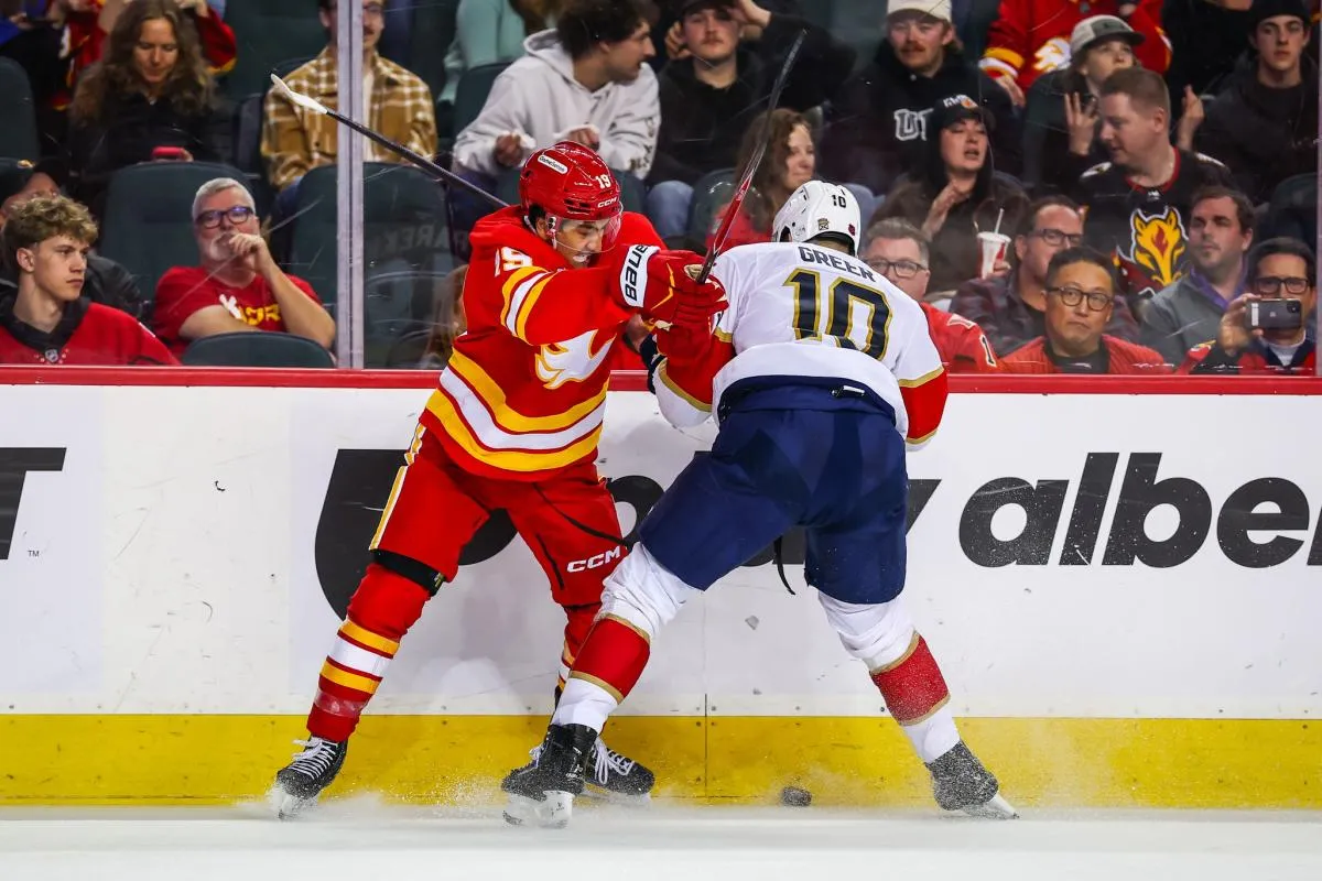 Calgary Flames defenseman Zayne Parekh (19) and Florida Panthers left wing A.J. Greer (10) battle for the puck during the third period at Scotiabank Saddledome.