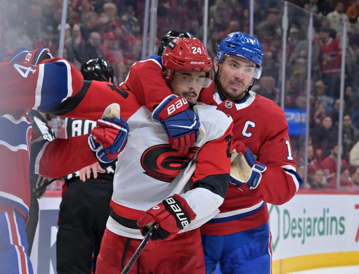 L'attaquant des Canadiens de Montréal Nick Suzuki (14) empêche l'attaquant des Hurricanes de la Caroline Seth Jarvis (24) de retenir le défenseur des Canadiens de Montréal Lane Hutson (48) au cours de la deuxième période au Centre Bell.